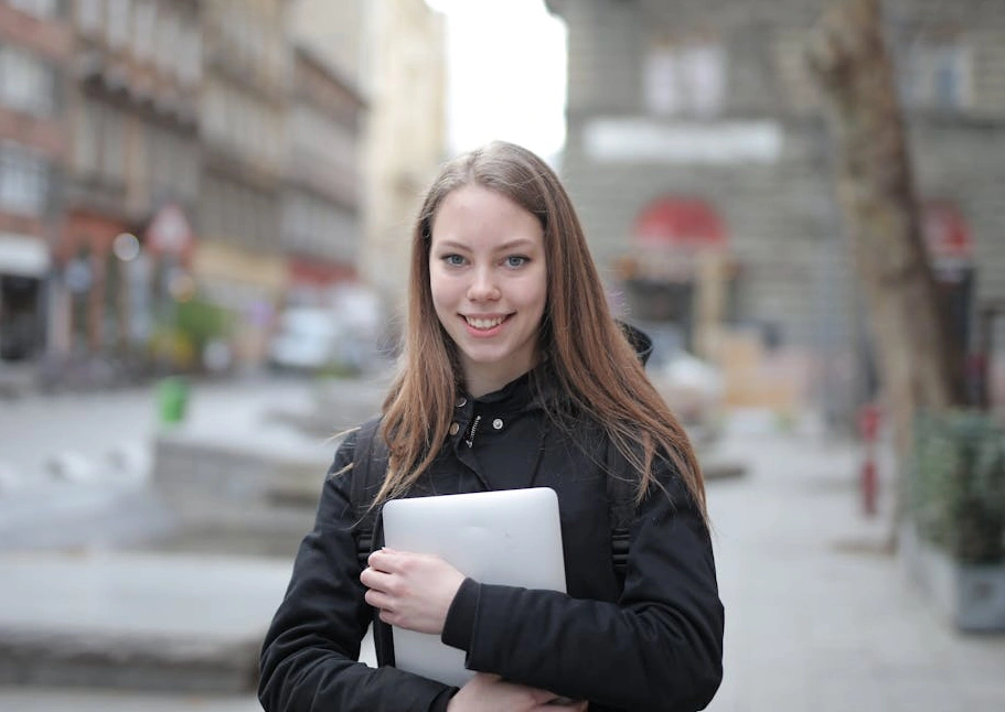 Estudiante sonriente con un portátil en un entorno de aprendizaje moderno.